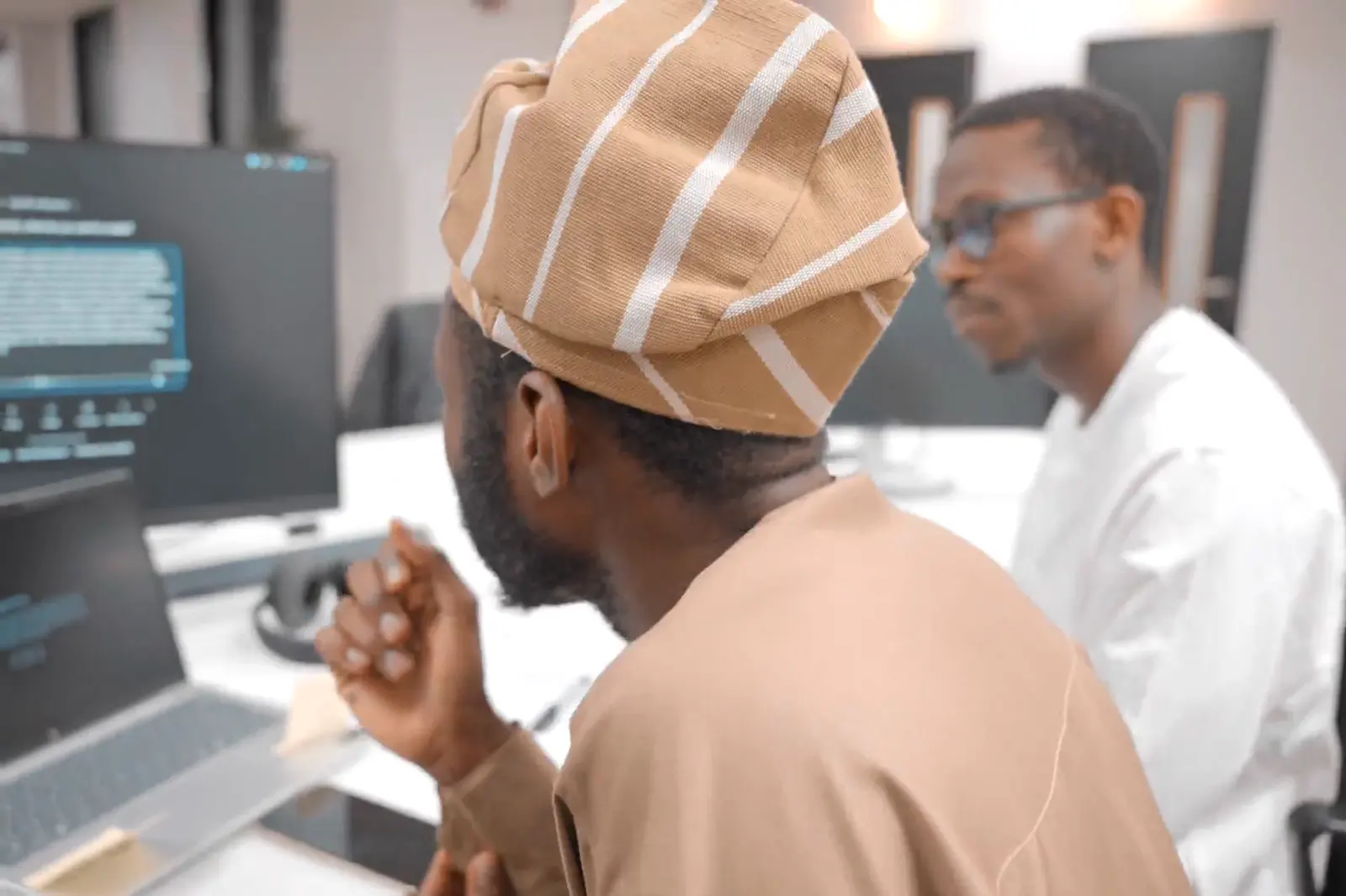 Two participants reviewing work on a monitor